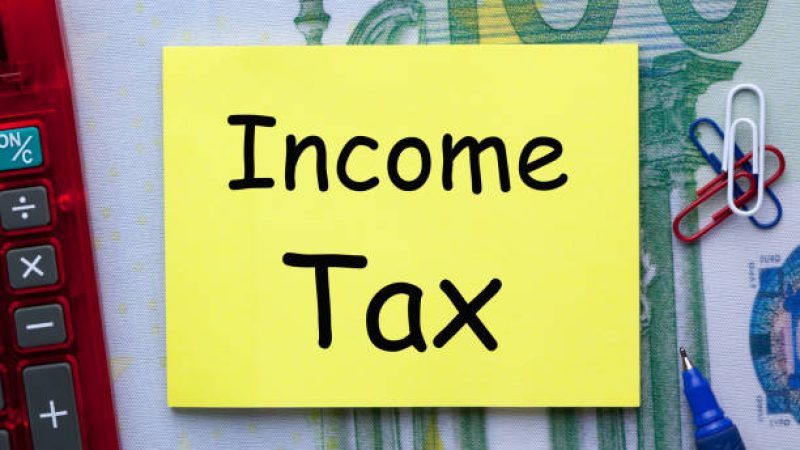 Income tax written on note with pen a side and office supplies.Concept of Taxation