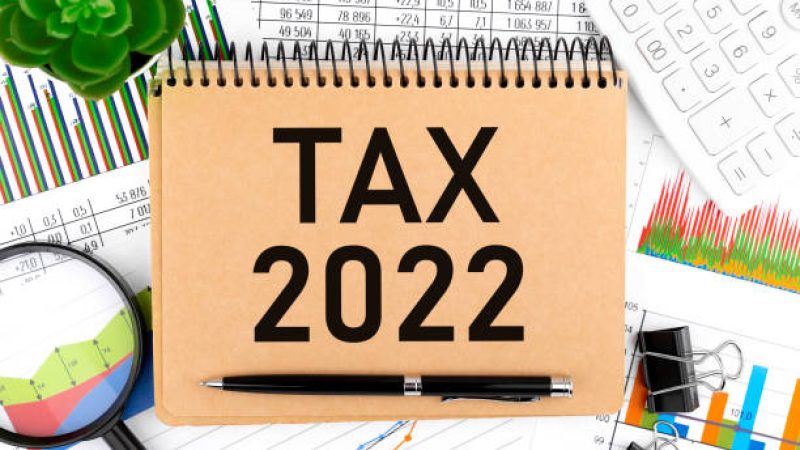 Text TAX 2022 on note pad, calculator, chart, magnifier. Accounting concept. Flat lay.
